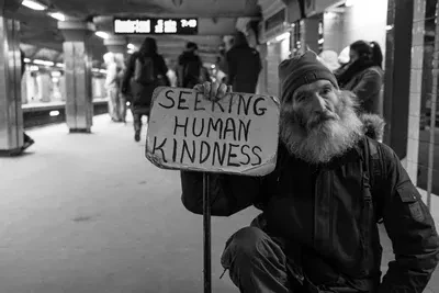 Man holding card with seeking human kindness text by  Matt Collamer on Unsplash